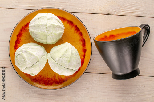 Sweet delicious pear marshmallow with ceramic saucer and cup on wooden table, macro, top view.