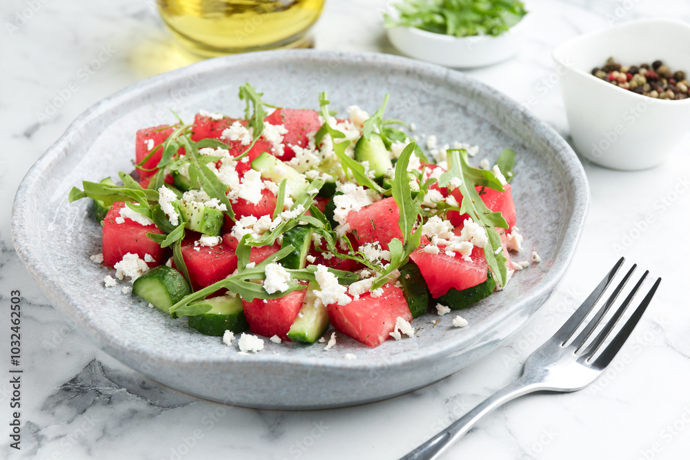 Delicious watermelon salad with feta cheese, cucumber and arugula served on white marble table, closeup Delicious watermelon salad with feta cheese, cucumber and arugula served on white marble table, closeup