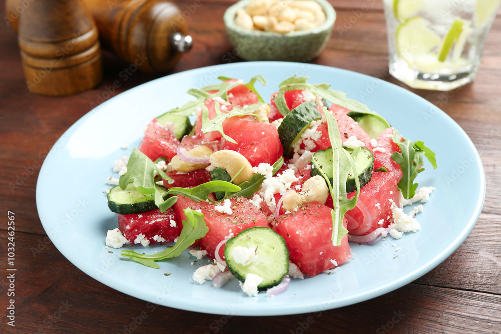 Tasty salad with watermelon, feta cheese, cashews and arugula on wooden table Tasty salad with watermelon, feta cheese, cashews and arugula on wooden table