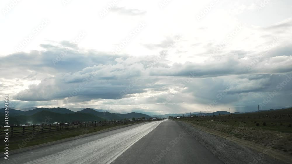 Paved road stretches through a flat plain, leading toward distant hills under a partly cloudy sky. The landscape showcases a tranquil countryside, inviting a sense of freedom and adventure Paved road stretches through a flat plain, leading toward distant hills under a partly cloudy sky. The landscape showcases a tranquil countryside, inviting a sense of freedom and adventure