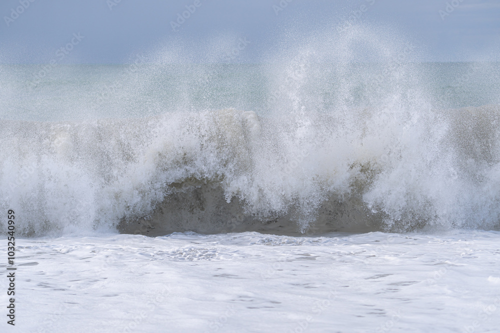 The ocean is rough and the waves are crashing against the shore. The sky is cloudy and the water is a deep blue color The ocean is rough and the waves are crashing against the shore. The sky is cloudy and the water is a deep blue color