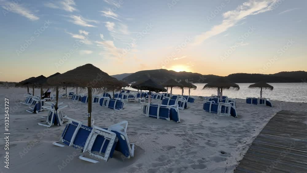 A tranquil beach scene at sunset with straw umbrellas and folded beach chairs facing the calm sea, creating a peaceful and relaxing atmosphere on the sandy shore. A tranquil beach scene at sunset with straw umbrellas and folded beach chairs facing the calm sea, creating a peaceful and relaxing atmosphere on the sandy shore.