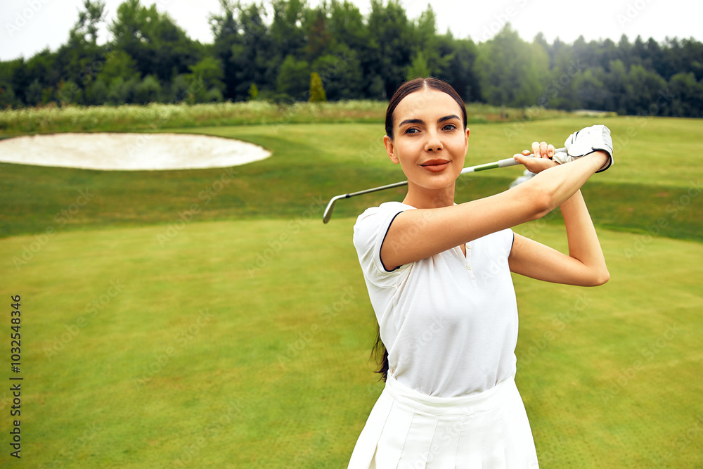 A cheerful and smiling golfer practicing their swing on the beautiful golf course today A cheerful and smiling golfer practicing their swing on the beautiful golf course today