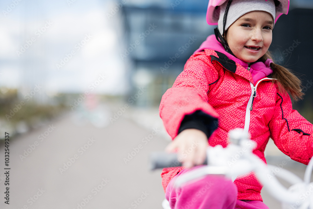 Smiling young girl cycling outdoors in winter clothing Smiling young girl cycling outdoors in winter clothing