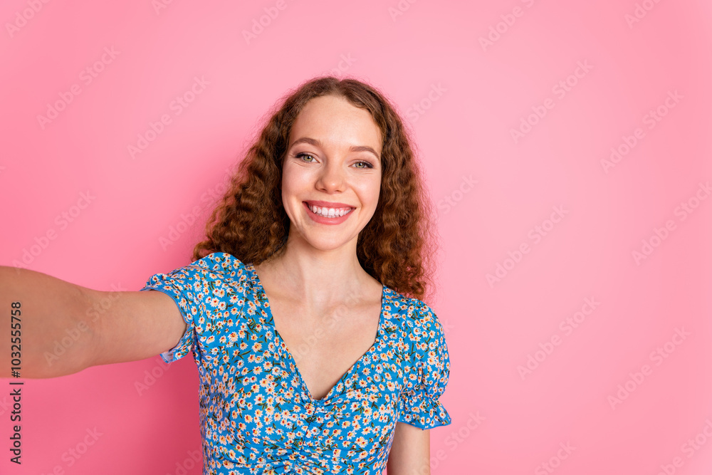 Smiling woman taking a cheerful selfie against pink background Smiling woman taking a cheerful selfie against pink background