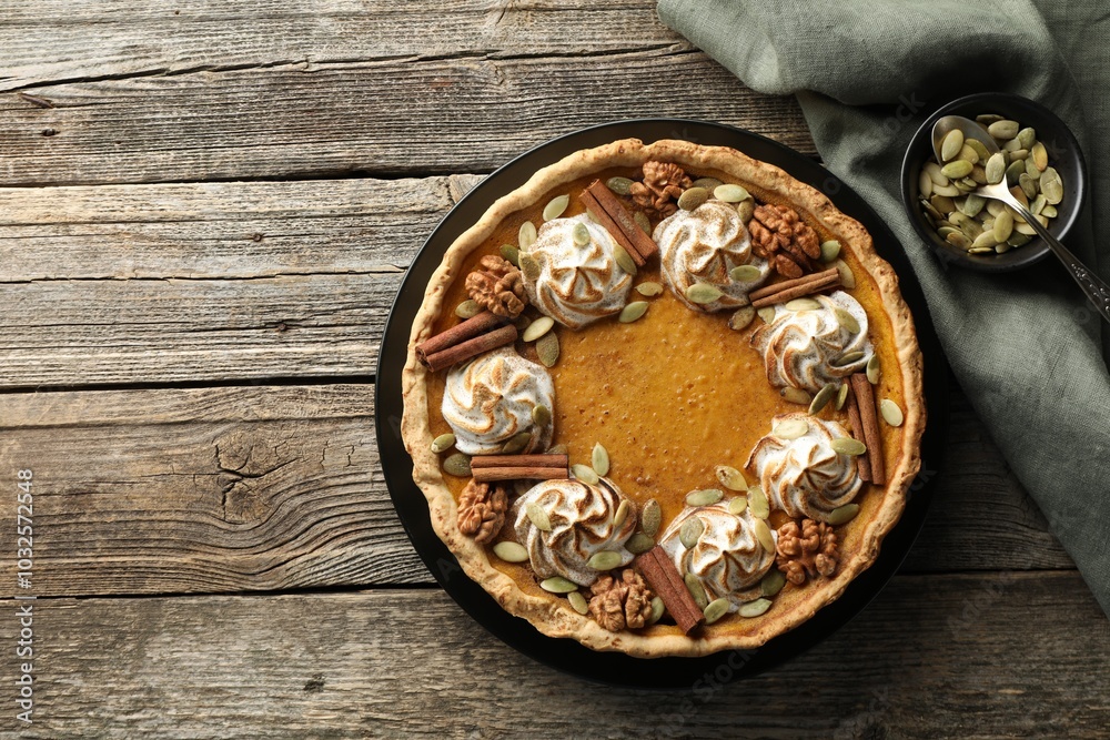 Homemade pumpkin pie with whipped cream, seeds and cinnamon on wooden table, top view. Space for text Homemade pumpkin pie with whipped cream, seeds and cinnamon on wooden table, top view. Space for text
