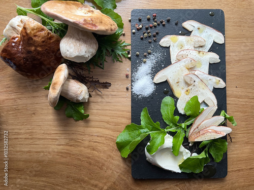 Obraz na płótnie Porcini mushroom carpaccio seasdoned with salt, pepper and olive oil. Fancy fresh forest dish served on a black stone on wooden background. w salonie