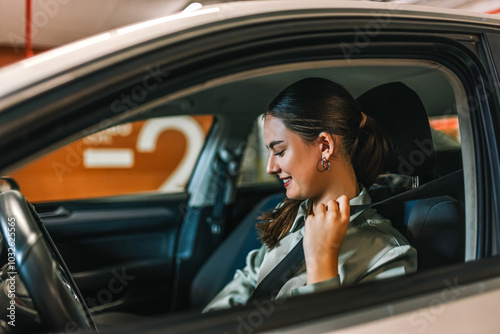 Young businesswoman putting a seatbelt on. Ready to drive off from his parking spot in an underground garage. photo