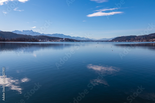 Panoramic view of alpine Lake Wörth surrounded by majestic mountains of Karawanks in Carinthia, Austria, Europe. Crystal-clear waters shimmer in sunlight. Viewing platform Hohe Gloriette, Pörtschach