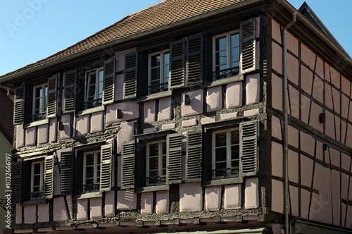 Ancient house under tile roof. Windows with wooden shutters. Authentic architecture in Riquewihr village, the Haut-Rhin department,  Grand Est in north-eastern France. Travel and tourism concept