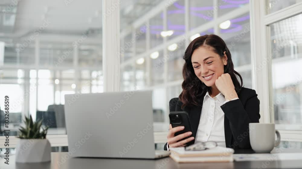 Excited businesswoman reading good news on her phone and celebrating success in office. Happy businesswoman working with laptop and phone.