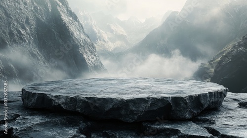 Misty mountain range with a large rock platform amidst dramatic clouds at dawn
