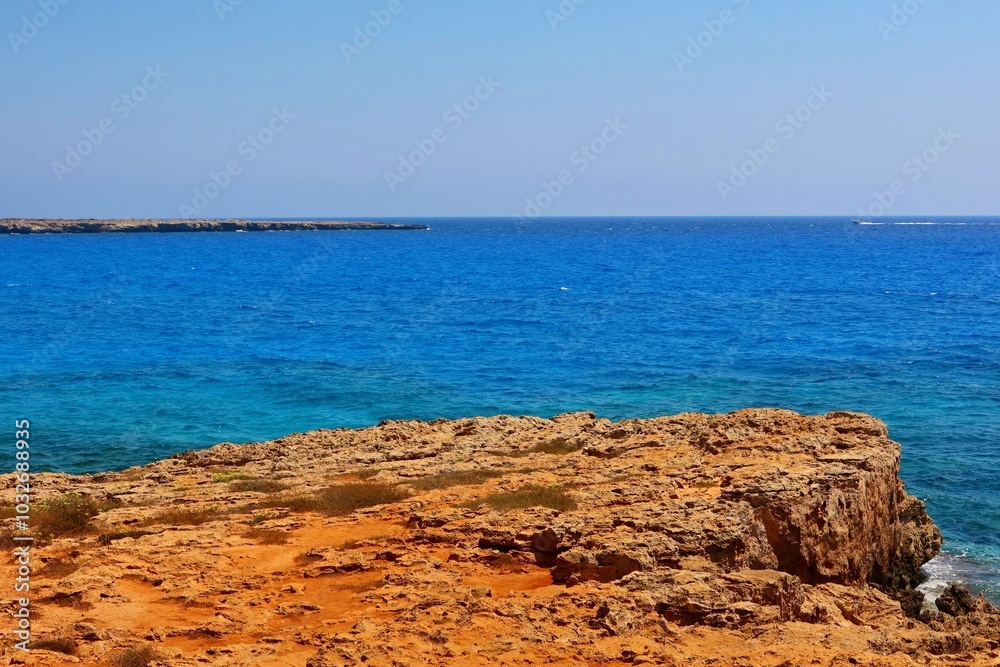 Vivid rocky coastline, blue calm sea and small fast boat, shore with the stones. Blue sky and sunny summer day, horizon and rock. Sea and ship Adventure trip, travel picture. Vivid rocky coastline, blue calm sea and small fast boat, shore with the stones. Blue sky and sunny summer day, horizon and rock. Sea and ship Adventure trip, travel picture.