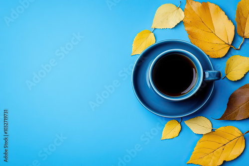 Blue saucer and cup of black coffee with yellow leaves next to it on a blue background with copy space