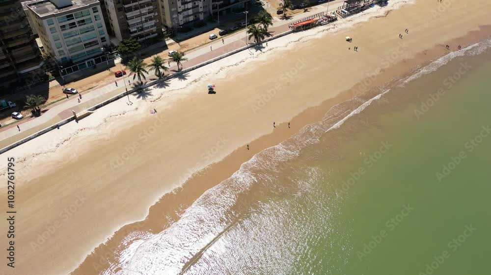 Imagem aérea de drone da Praia do Morro em um dia ensolarado, com pessoas passeando, praticando esportes e descansando ao sol. Cidade de Guarapari no Espírito Santo