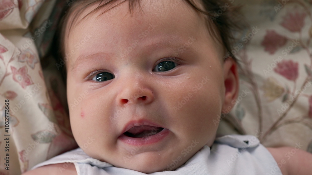 Baby lying on a patterned blanket, looking directly at the camera with a calm expression. The focus is on the baby’s facial features, capturing a moment of innocence and serenity Baby lying on a patterned blanket, looking directly at the camera with a calm expression. The focus is on the baby’s facial features, capturing a moment of innocence and serenity