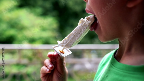 Fotografia Child enjoying an ice cream outdoors, licking a homemade popsicle on a sunny day