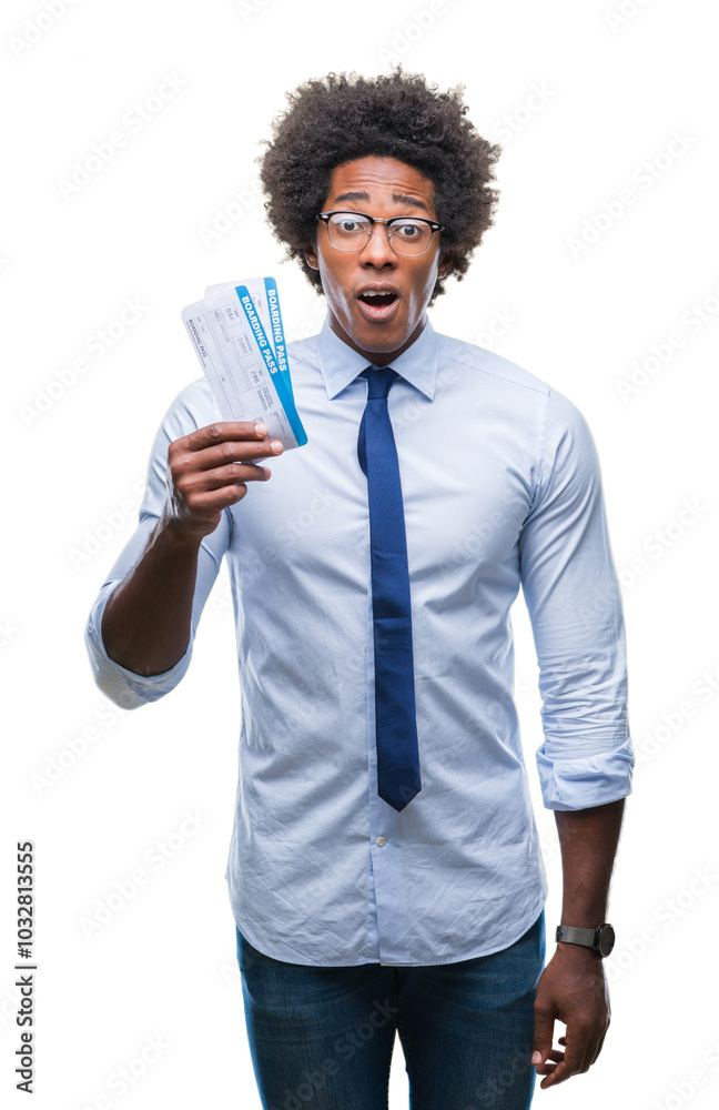 Afro american man holding boarding pass over isolated background scared in shock with a surprise face, afraid and excited with fear expression Afro american man holding boarding pass over isolated background scared in shock with a surprise face, afraid and excited with fear expression
