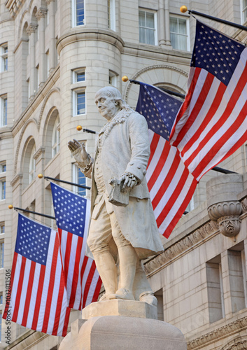 Old Post Office building with Benjamin Franklin Statue surrounded by American flags, Washington DC, United States