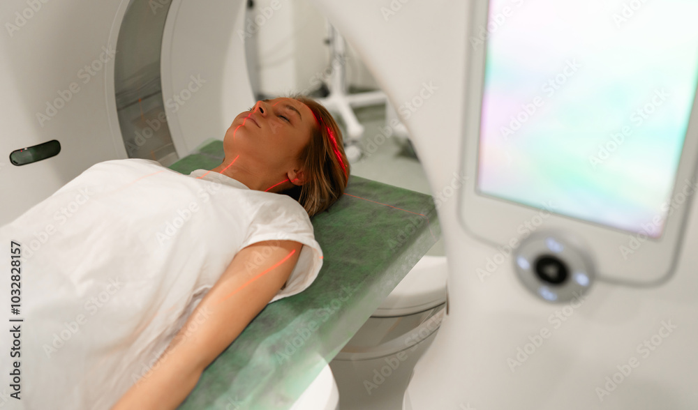 Woman patient lies on an MRI scanner bed with laser alignment beams on their body, preparing for a detailed diagnostic scan in a modern medical facility focused on advanced imaging technology. Woman patient lies on an MRI scanner bed with laser alignment beams on their body, preparing for a detailed diagnostic scan in a modern medical facility focused on advanced imaging technology.