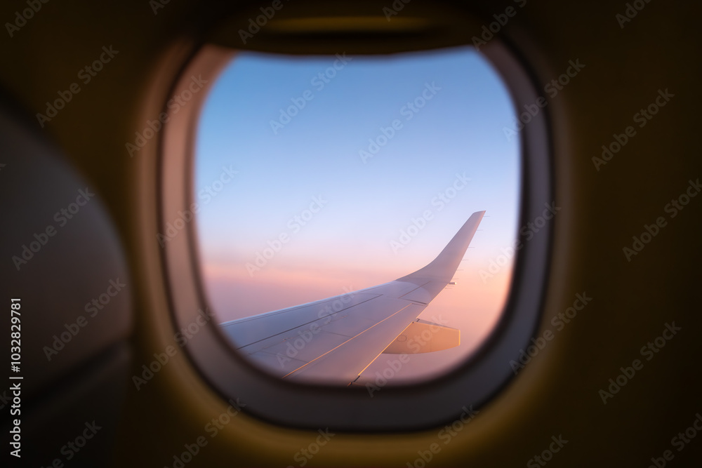 Naklejka premium View of airplane wing through window during flight at sunset - Landscape