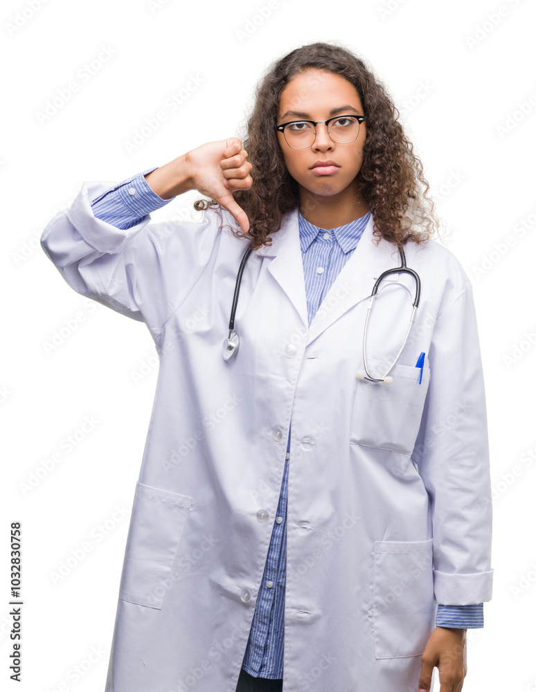 Young hispanic doctor woman with angry face, negative sign showing dislike with thumbs down, rejection concept Young hispanic doctor woman with angry face, negative sign showing dislike with thumbs down, rejection concept