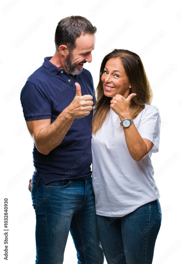 Naklejka premium Middle age hispanic casual couple over isolated background doing happy thumbs up gesture with hand. Approving expression looking at the camera with showing success.