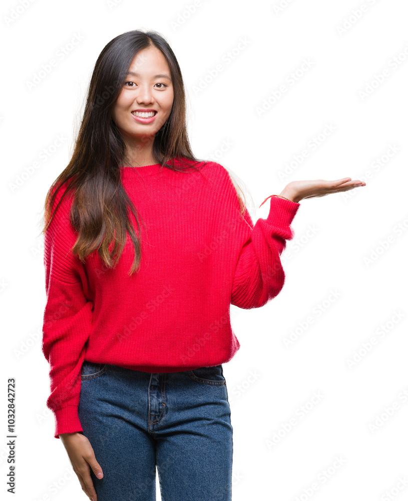 Young asian woman wearing winter sweater over isolated background smiling cheerful presenting and pointing with palm of hand looking at the camera. Young asian woman wearing winter sweater over isolated background smiling cheerful presenting and pointing with palm of hand looking at the camera.