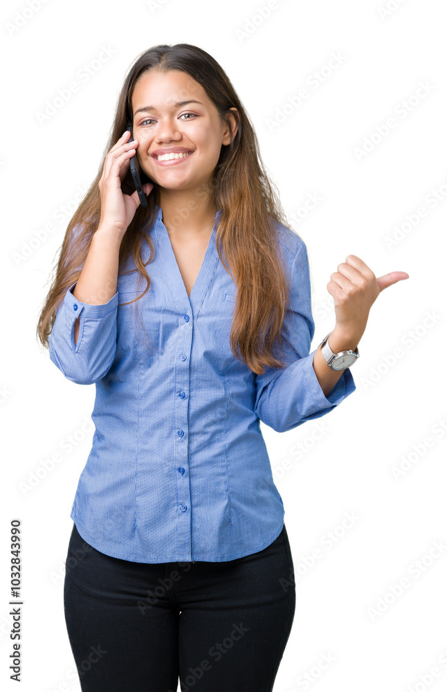 Young beautiful brunette business woman talking on smartphone over isolated background pointing and showing with thumb up to the side with happy face smiling
