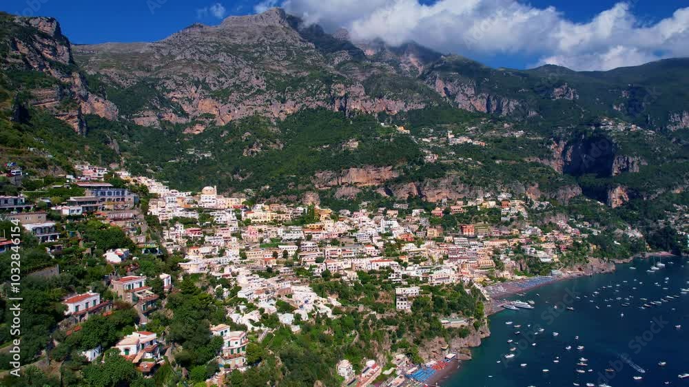 4K Aerial Drone video of a magical town nested in the surrounding mountains with colorful houses with the view on the beach and boats the sea on a warm sunny day, Positano, Italy, famous Amalfi coast