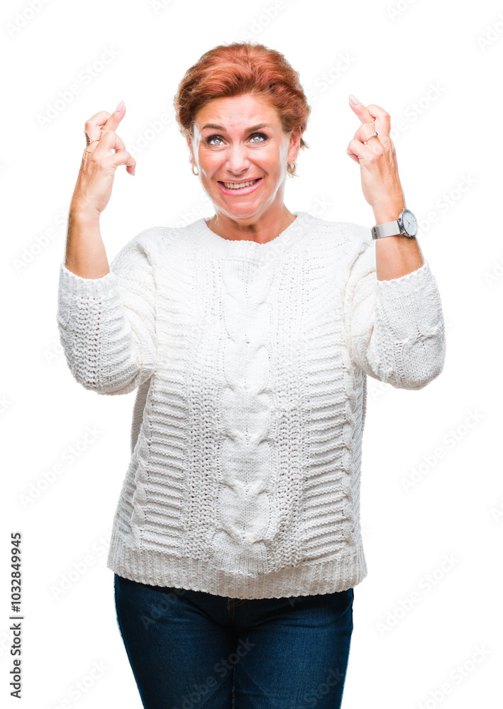 Atrractive senior caucasian redhead woman wearing winter sweater over isolated background smiling crossing fingers with hope and eyes closed. Luck and superstitious concept. Atrractive senior caucasian redhead woman wearing winter sweater over isolated background smiling crossing fingers with hope and eyes closed. Luck and superstitious concept.