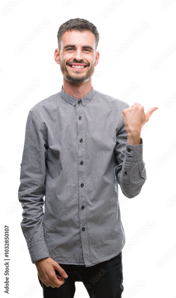 Young hipster man smiling with happy face looking and pointing to the side with thumb up.