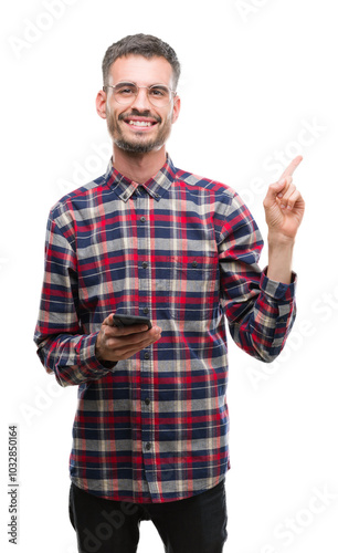 Young hipster adult man holding smartphone very happy pointing with hand and finger to the side