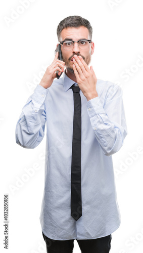 Young business adult man talking on the phone cover mouth with hand shocked with shame for mistake, expression of fear, scared in silence, secret concept