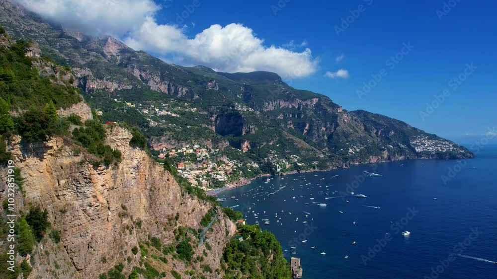 4K Aerial Drone video of a magical town nested in the surrounding mountains with colorful houses with the view on the beach and boats the sea on a warm sunny day, Positano, Italy, famous Amalfi coast