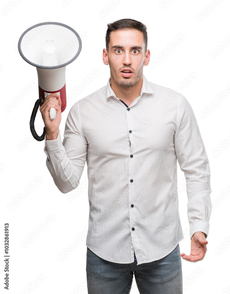 Handsome young man holding microphone scared in shock with a surprise face, afraid and excited with fear expression Handsome young man holding microphone scared in shock with a surprise face, afraid and excited with fear expression