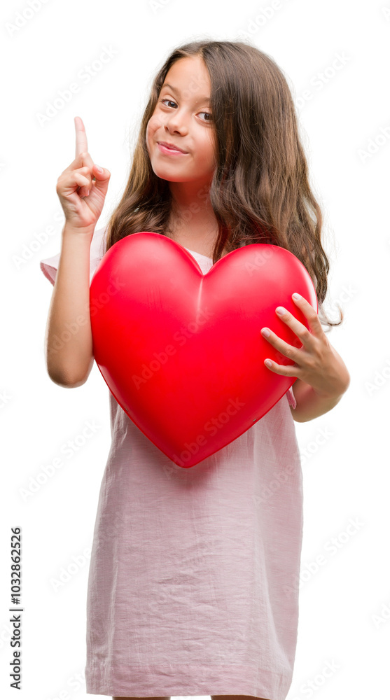 Brunette hispanic girl holding red heart surprised with an idea or question pointing finger with happy face, number one Brunette hispanic girl holding red heart surprised with an idea or question pointing finger with happy face, number one