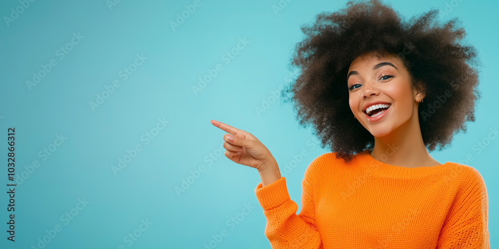 Smiling woman in orange sweater pointing against blue background Smiling woman in orange sweater pointing against blue background