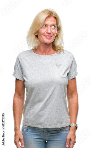 Middle age blonde woman over isolated background smiling looking side and staring away thinking.