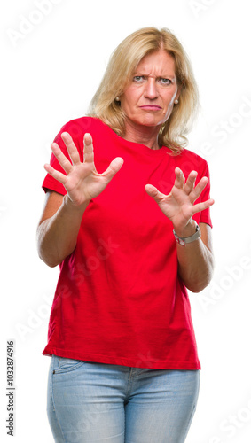 Middle age blonde woman over isolated background disgusted expression, displeased and fearful doing disgust face because aversion reaction. With hands raised. Annoying concept.