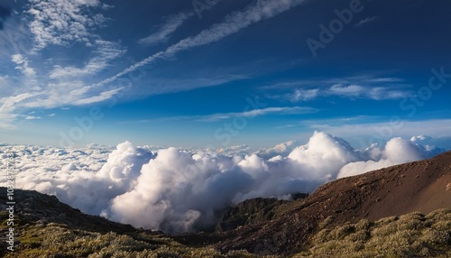 Big clouds over the mountains; A view above the clouds from the top of the mountain; landscape photography; large cumulus clouds in the open blue skies from above the mountain; scenic photography