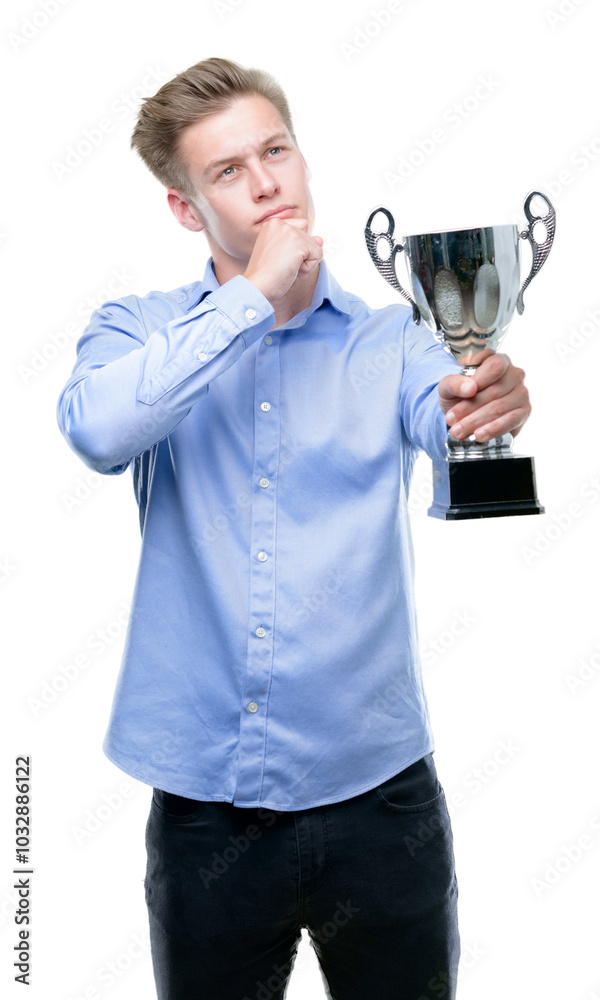 Young handsome blond man holding a trophy serious face thinking about question, very confused idea Young handsome blond man holding a trophy serious face thinking about question, very confused idea