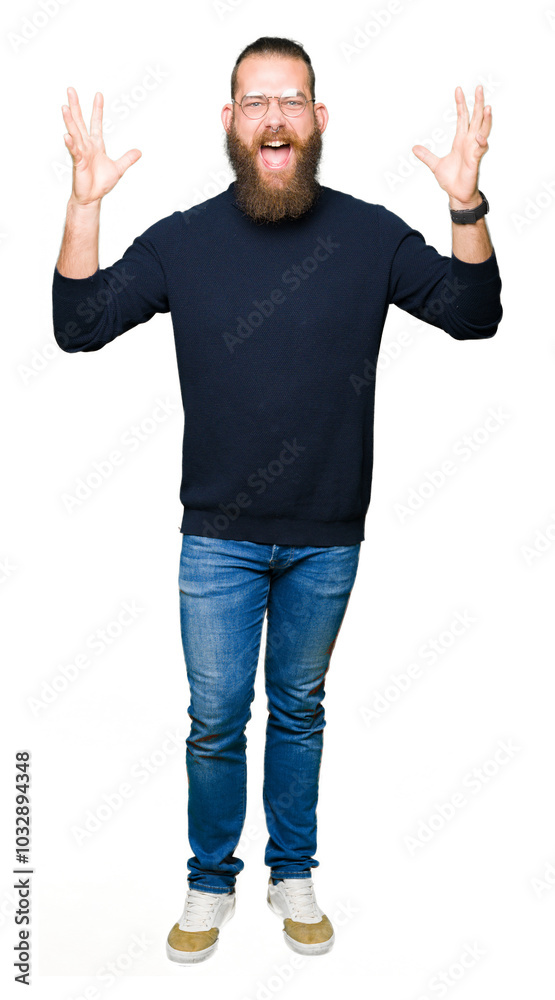 Young blond man wearing glasses and turtleneck sweater celebrating crazy and amazed for success with arms raised and open eyes screaming excited. Winner concept Young blond man wearing glasses and turtleneck sweater celebrating crazy and amazed for success with arms raised and open eyes screaming excited. Winner concept