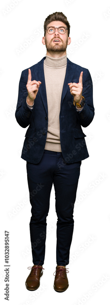 Young handsome business man wearing glasses amazed and surprised looking up and pointing with fingers and raised arms. Young handsome business man wearing glasses amazed and surprised looking up and pointing with fingers and raised arms.