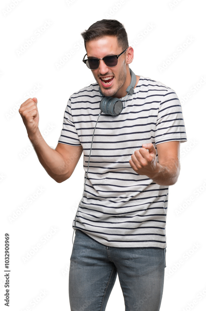 Handsome young man wearing headphones very happy and excited doing winner gesture with arms raised, smiling and screaming for success. Celebration concept. Handsome young man wearing headphones very happy and excited doing winner gesture with arms raised, smiling and screaming for success. Celebration concept.
