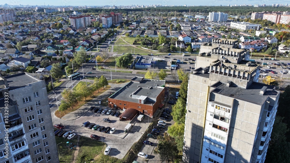 Obraz premium Minsk, Belarus - 27.10.2024: Dense building of a modern large Belarusian city. Neighborhood of one-storey huts, cottages and multi-storey residential buildings. View of the city of Minsk from a height