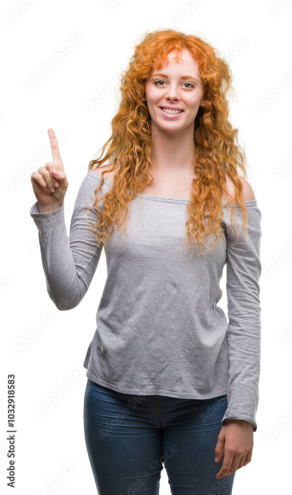 Young redhead woman showing and pointing up with finger number one while smiling confident and happy. Young redhead woman showing and pointing up with finger number one while smiling confident and happy.