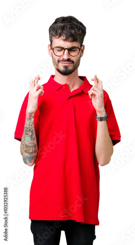 Young handsome man wearing glasses over isolated background smiling crossing fingers with hope and eyes closed. Luck and superstitious concept.