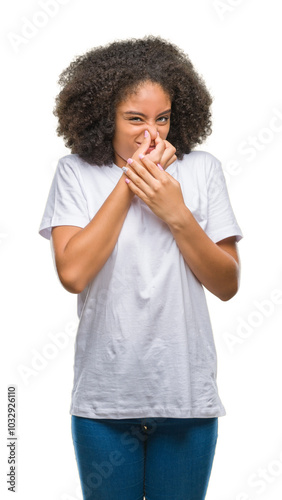 Young afro american woman over isolated background smelling something stinky and disgusting, intolerable smell, holding breath with fingers on nose. Bad smells concept. photo