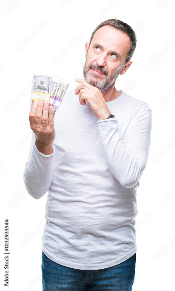 Senior hoary man holding buch of dollars over isolated background serious face thinking about question, very confused idea Senior hoary man holding buch of dollars over isolated background serious face thinking about question, very confused idea